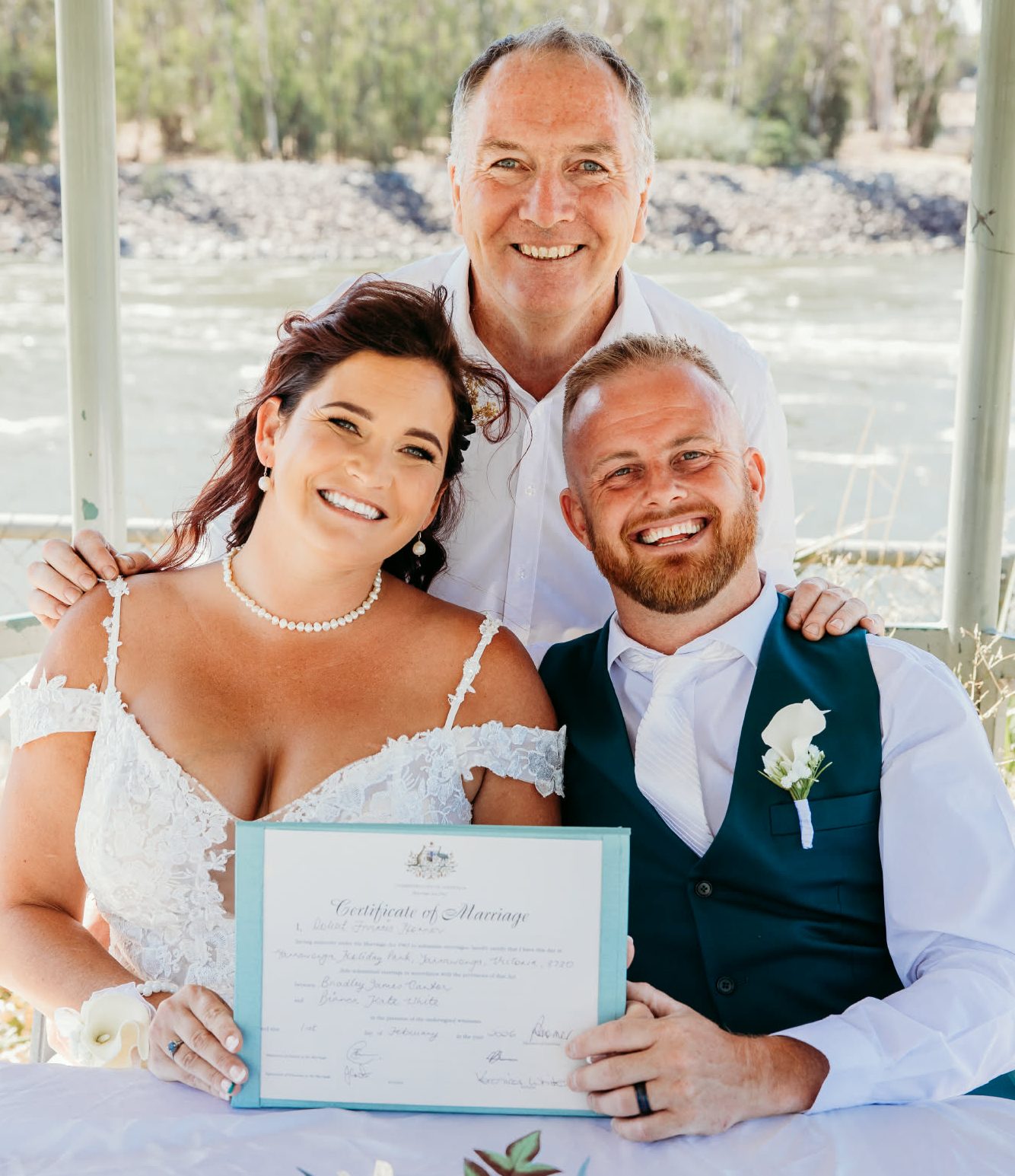 Bride and Groom happily holding their marriage certificate with officiant